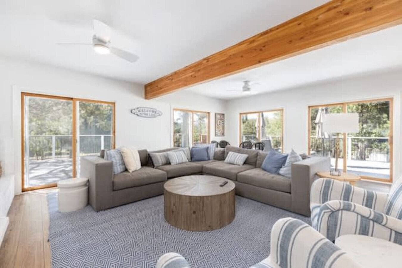 A modern living room with a sectional sofa, a round coffee table, and striped armchairs.
