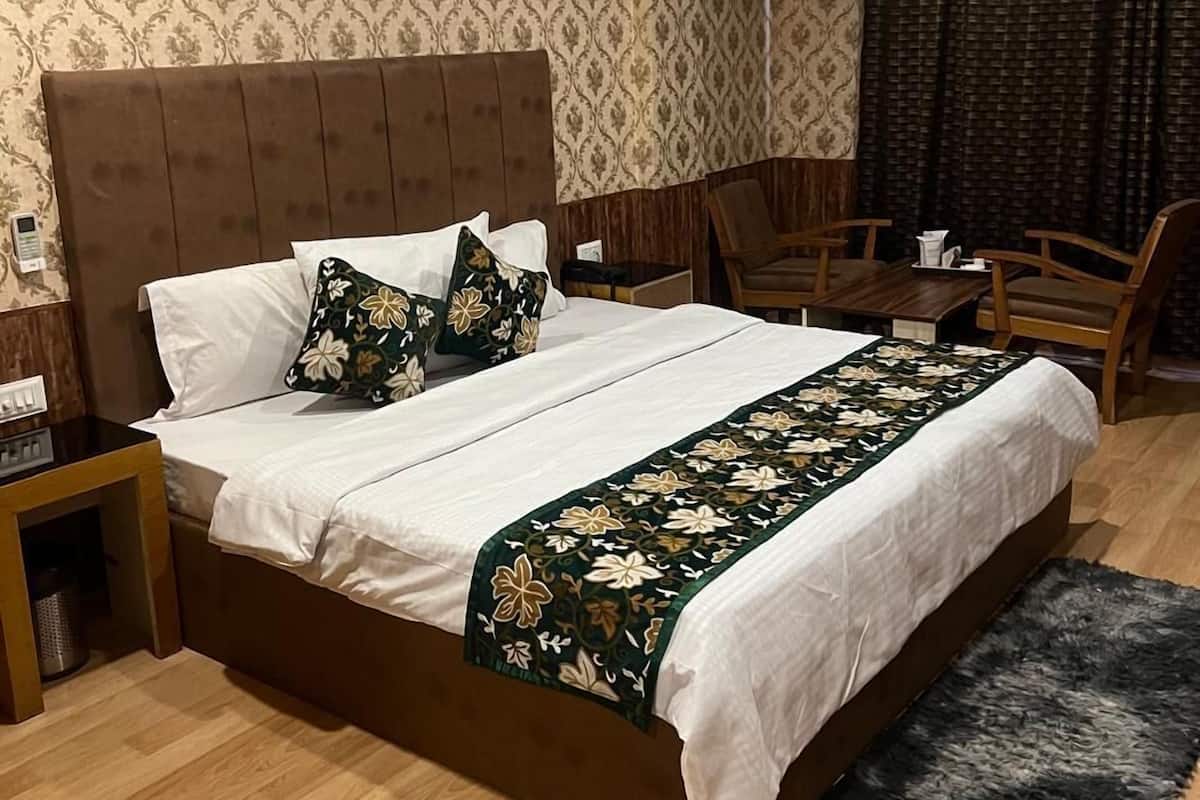 A neatly made bed with a floral bedspread, a wooden headboard, and a small bedside table with a lamp.