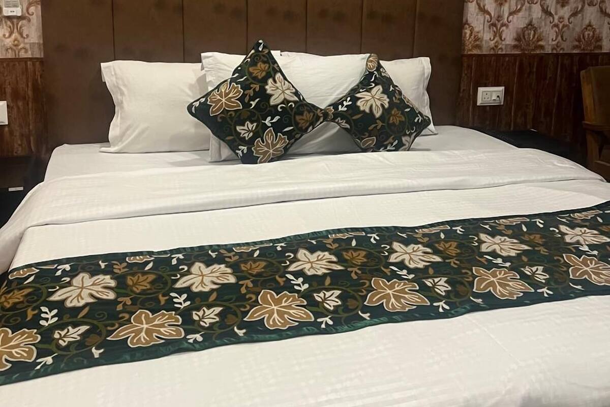 A neatly made bed with a floral-patterned bedspread and two decorative pillows.