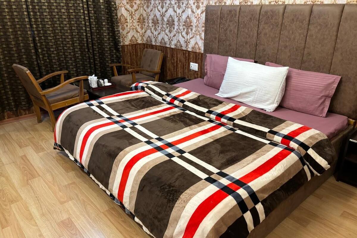 A hotel room with a bed, a wooden chair, a small table, and a nightstand.