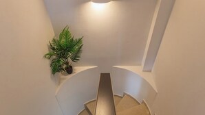 A spiral staircase with a handrail, a light fixture on the ceiling, and a potted plant on the wall. - Villa Blu Mare Relax Place in Nafpaktos! (NAFPAKTOS)