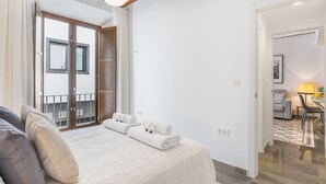 A bedroom with a large bed, a wooden ceiling, a balcony, and a view of the outside. - Luxury Suite Dar Garnata (Granada)