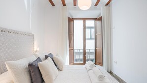 A hotel room with a large bed, a patterned headboard, and a view of the outside through a glass door. - Luxury Suite Dar Garnata (Granada)