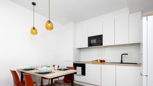 Une cuisine moderne avec des meubles blancs, un micro-ondes noir et un plan de travail en bois.