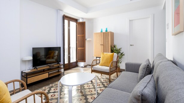 Un salon moderne comprenant un canapé, un téléviseur, un meuble en bois et une table à manger.