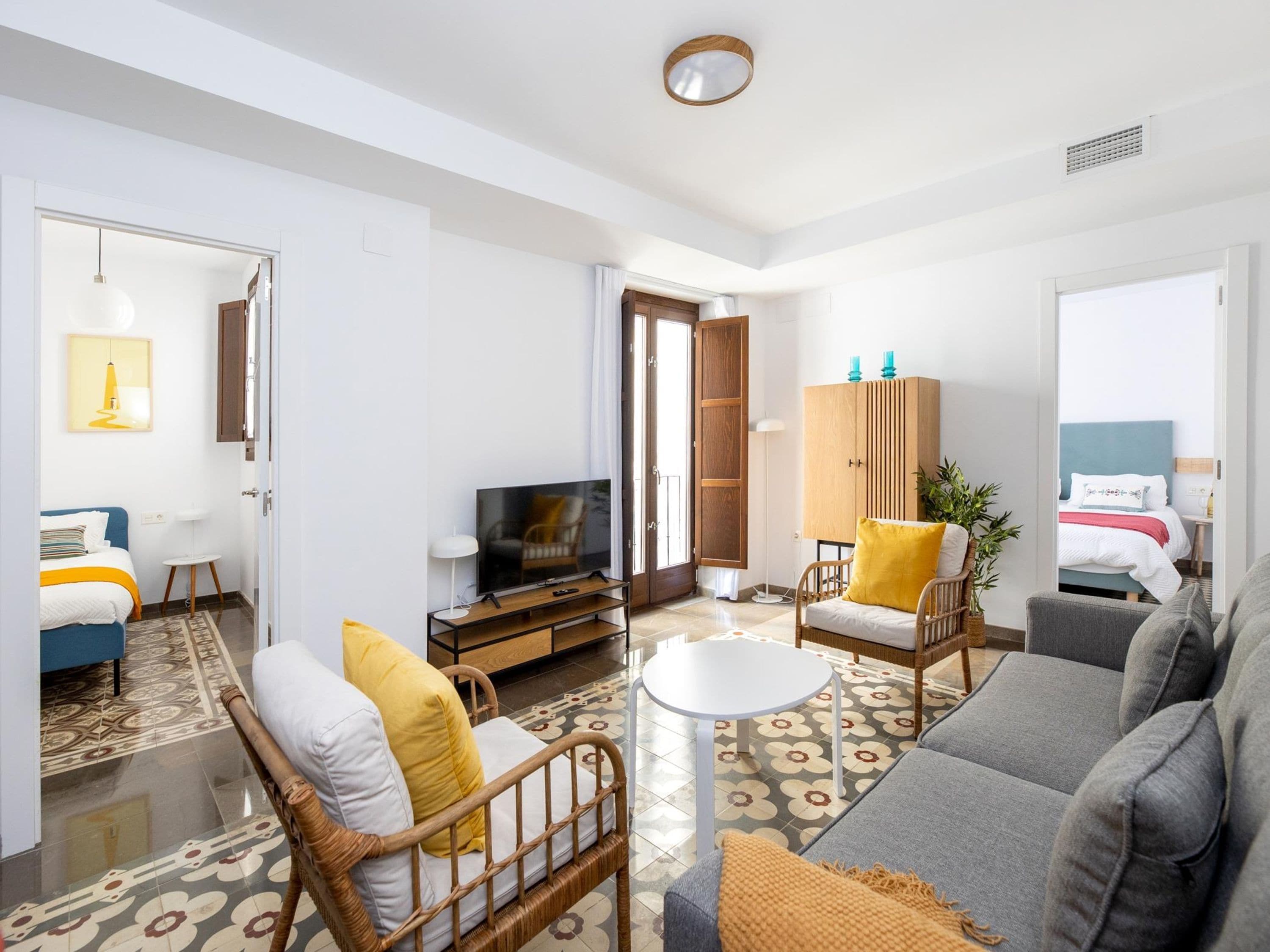 Un salon moderne comprenant un canapé, des fauteuils, un téléviseur et un meuble.