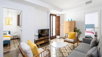 A modern living room with a sofa, armchairs, a TV, and a cabinet.