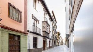 Une rue étroite bordée d’immeubles à plusieurs étages, agrémentée de balcons et présentant des éléments d’architecture traditionnels.