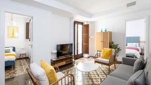 Un salon moderne comprenant un canapé, des fauteuils, un téléviseur et un meuble.
