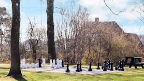 A park with a chessboard layout, trees, and a building in the background.