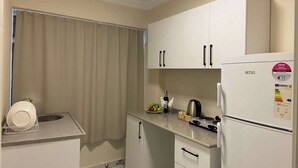 A compact kitchen with white cabinets, a stove, and a refrigerator. - PRUVA INN HOTEL (Antalya)