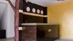 A reception desk with a wooden finish, a clock above it, and a yellow textured wall to the right.