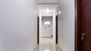 A narrow, well-lit hallway with a polished floor, leading to a room with a door on the right.