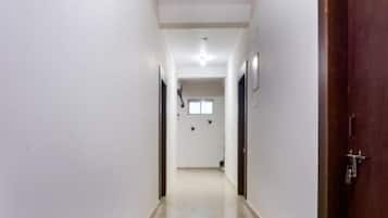 A narrow, well-lit hallway with a polished floor, leading to a room with a door on the right.