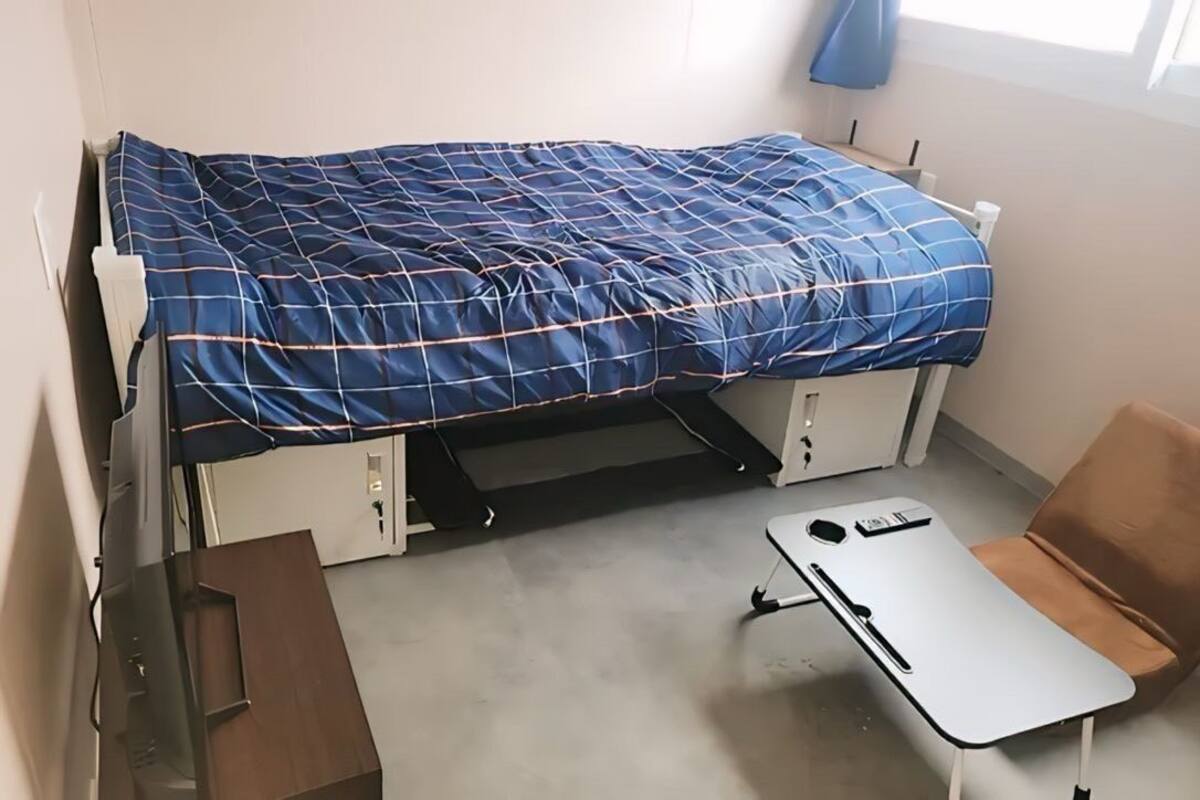 Een kleine kamer met een bed, een bureau en een stoel.