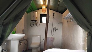 Een kleine, afgesloten ruimte met een bed, een wastafel en een toilet.
