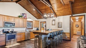 Una cocina amplia con armarios de madera, una isla grande y una pared decorativa de piedra.
