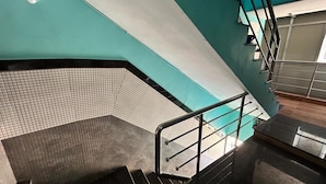 Una escalera con barandilla metálica, pared de azulejos y pared color turquesa.