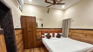 Un dormitorio con una cama de madera, un armario, un ventilador de techo y un espejo.