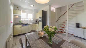 Et moderne køkken med spiseplads, en trappe og udsigt til stuen.
