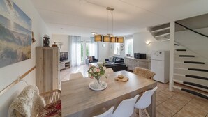 A modern kitchen with a dining area, a staircase, and a living room.
