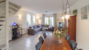 A modern living room with a sofa, dining table, and a staircase. - Spacious Coastal Getaway (Wemeldinge)