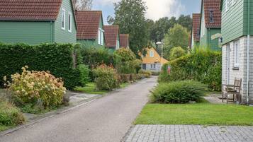 A residential street with houses, a paved road, and a brick pathway.