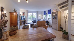 A spacious living area with a wooden dining table, sofas, and a television. - Holiday Home in Zeeland with Garden Terrace (Wemeldinge)