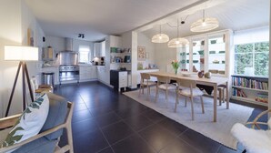 Una cucina moderna con zona pranzo, caratterizzata da una grande isola, luci a sospensione e vista sull'esterno.