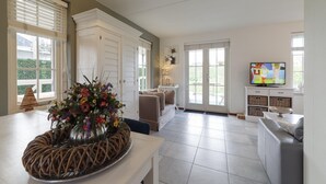 A spacious living area with a dining table, a sofa, and a television. - Charming Coastal Escape (Wemeldinge)