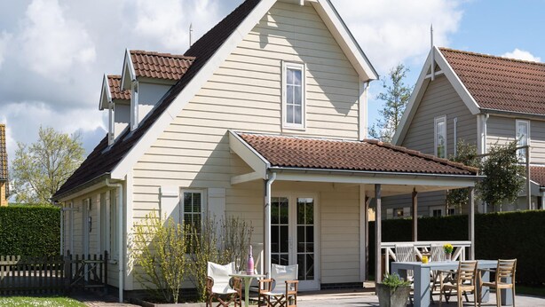 A two-story house with a covered patio and a fenced yard. - Charming Coastal Escape (Wemeldinge)