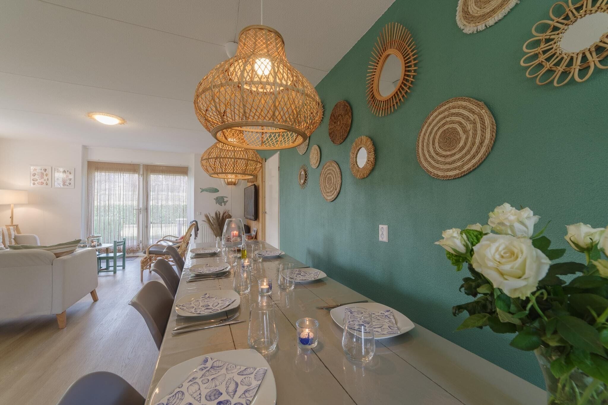 Een eethoek met een lange tafel gedekt voor een maaltijd, omringd door rieten lampen en geweven wanddecoraties.