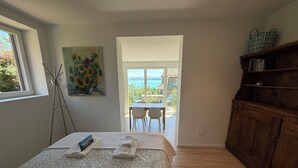 Een slaapkamer met een bed, een schilderij, een houten kast en uitzicht op buiten.
