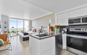 A modern kitchen with a central island, stainless steel appliances, and a view to the outside.