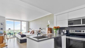 A modern kitchen with a central island, built-in appliances, and a large window overlooking a cityscape. - Spectacular Bay View Apartment in Coconut Grove (Miami)