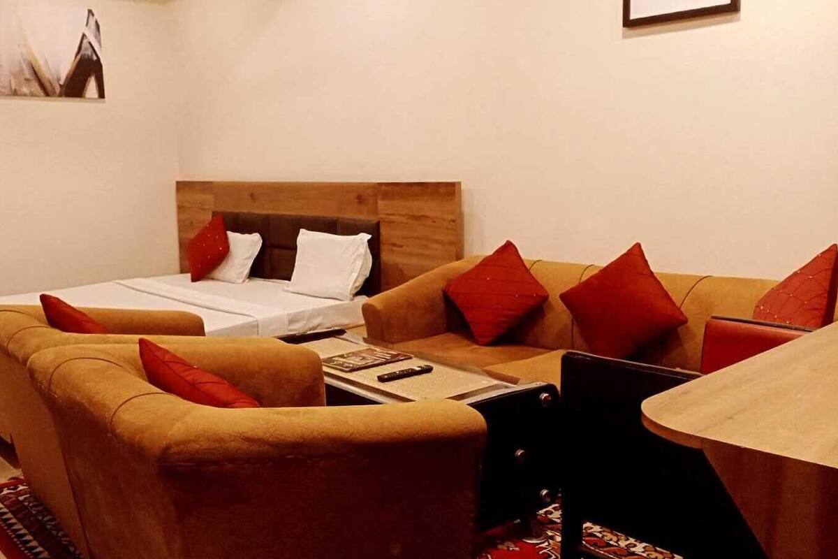 Una habitación de hotel acogedora con cama, sofá y una mesita con control remoto.