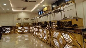 A spacious room with a long, reflective gold partition, ceiling fans, recessed lighting, and air conditioning units. - Deepak Hotel (Meerut)