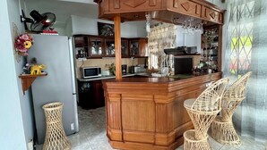 A kitchen with a wooden island, wicker chairs, and a microwave. - Villa Poisson Dans l 'eau (Trou aux Biches)