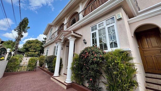 A two-story house with a balcony, a wooden door, and a brick pathway leading to the entrance. - Villa Poisson Dans l 'eau (Trou aux Biches)