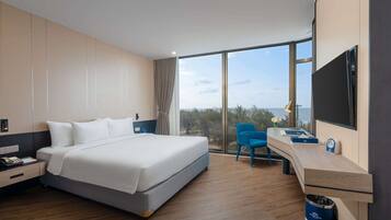 A modern hotel room with a large bed, a desk with a chair, a TV, and a view of the outdoors.