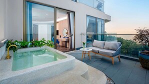 Un balcón exterior moderno con un jacuzzi, un sofá y una zona de comedor.