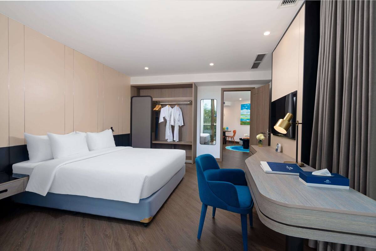 Una habitación de hotel moderna con cama, escritorio, silla y armario.