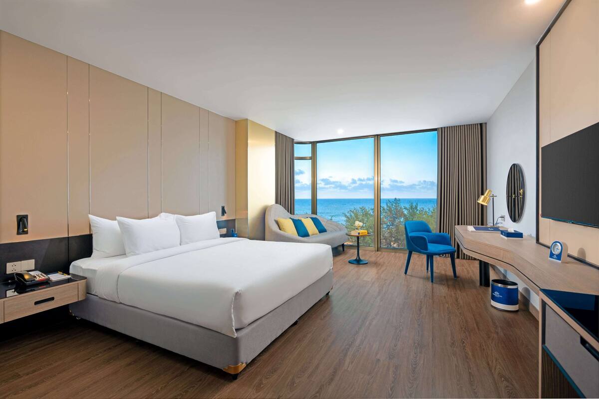 Una habitación de hotel moderna con una cama grande, un escritorio y vistas al mar.