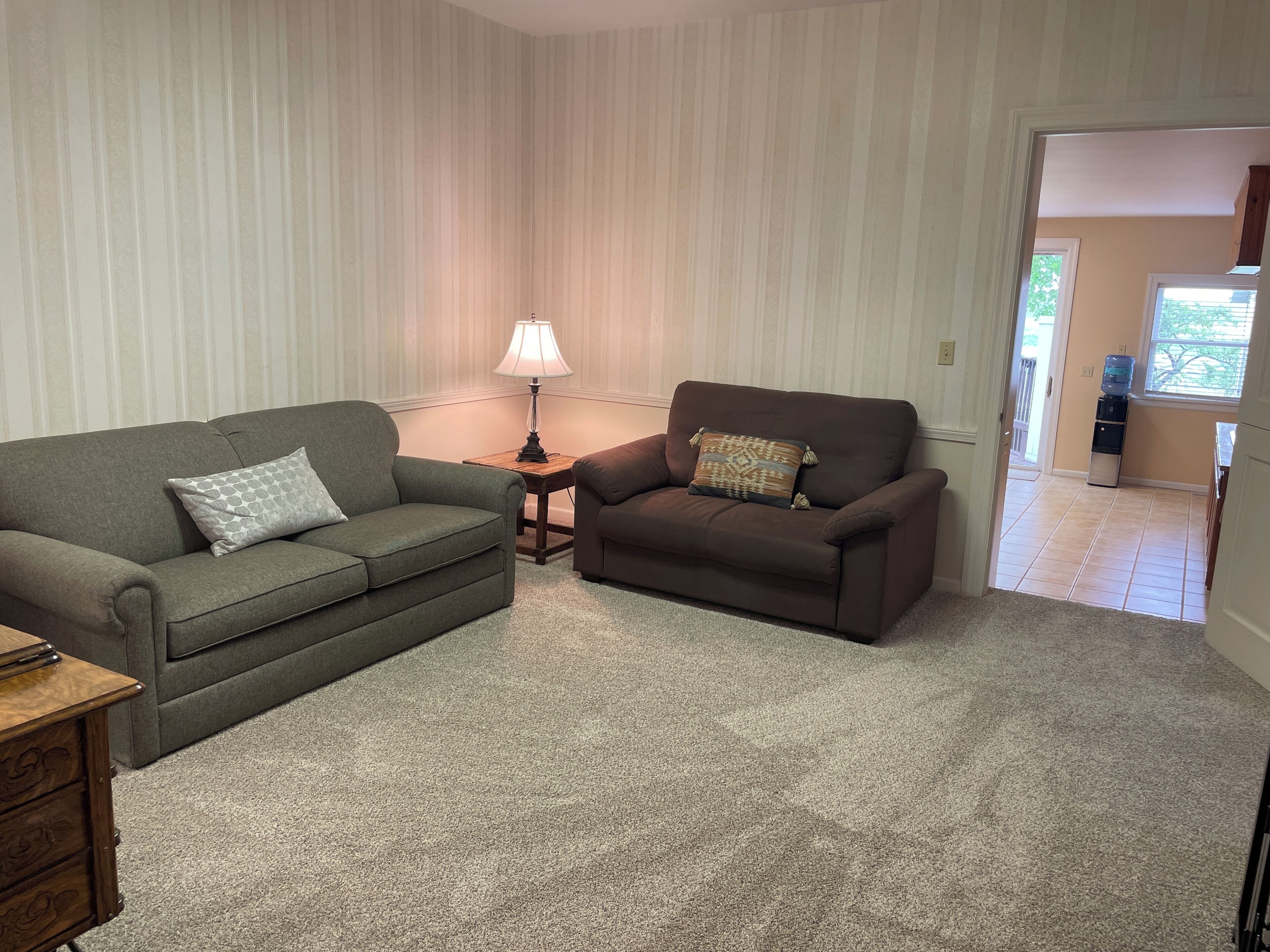 Ein Wohnzimmer mit zwei Sofas, einer Lampe und einem Wasserspender.