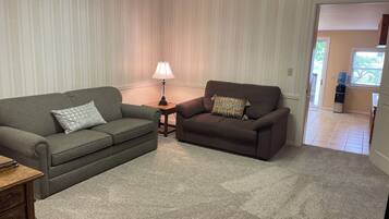 Ein Wohnzimmer mit zwei Sofas, einer Lampe und einem Wasserspender.