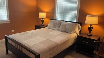 A bedroom with a bed, nightstands, lamps, and a chair.