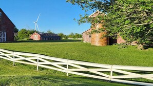 Un caserío rural con un molino, graneros y una valla blanca.