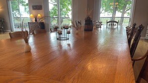 Una gran mesa de madera con sillas, una planta en maceta y velas.