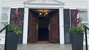 Entrada de un edificio con puertas dobles, un pequeño alero y dos macetas.