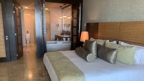 Ett hotellrum med en stor säng, en sänglampa och utsikt in i badrummet.